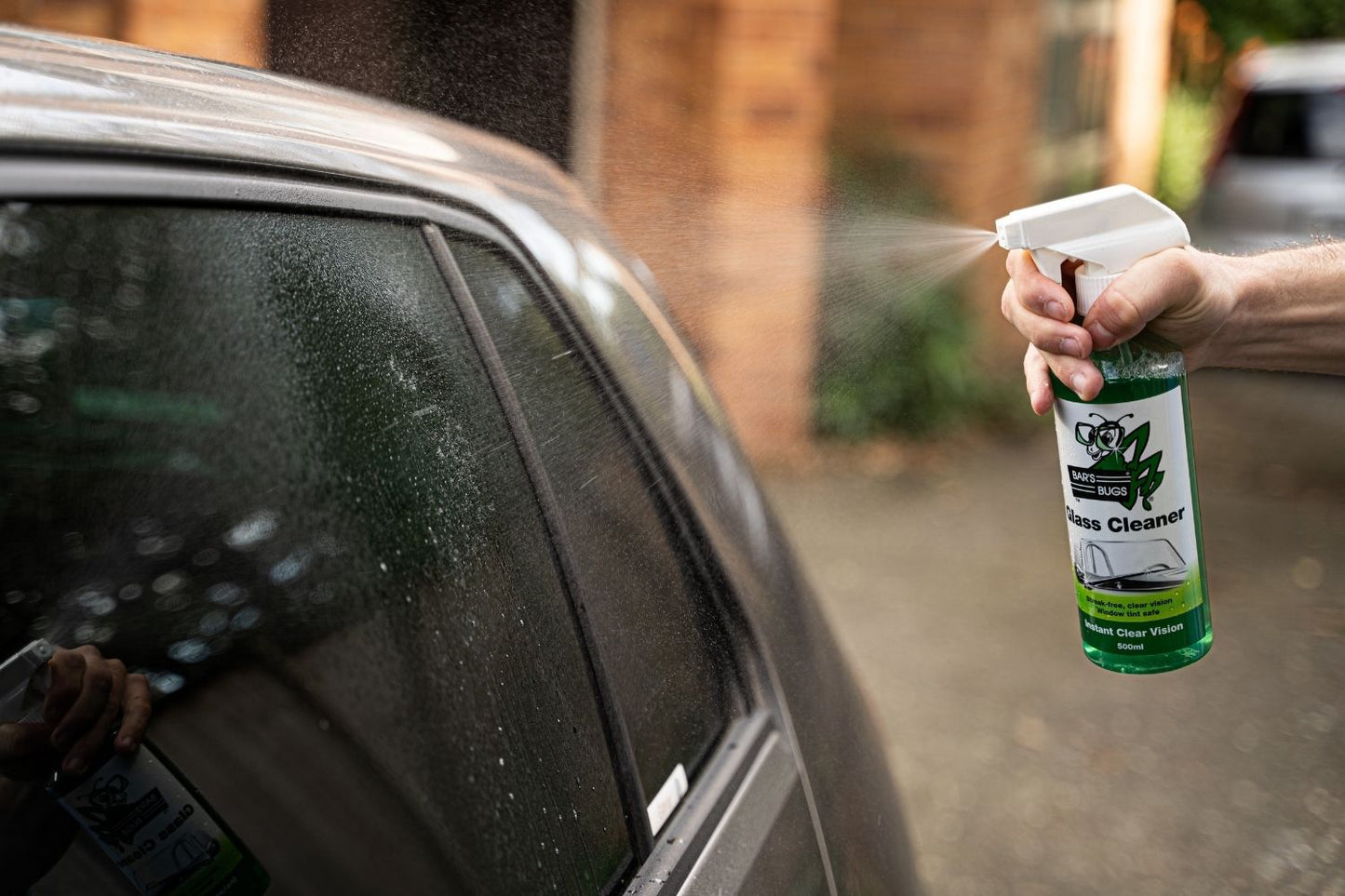 Spraying Bar's Bugs Glass Cleaner on exterior window of vehicle